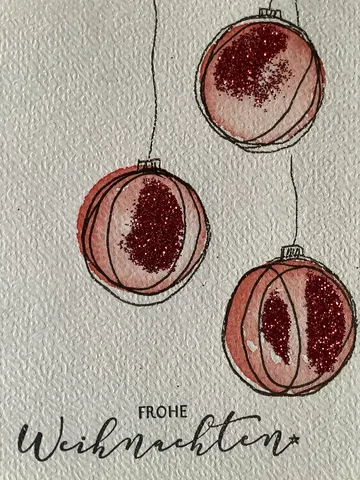 Three red glittery ornaments on textured paper.