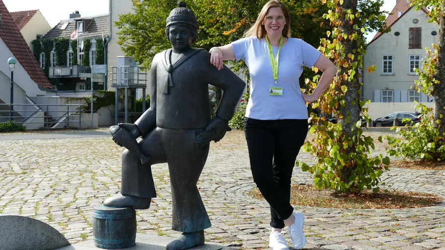 Woman posing with a sculpture in a plaza.
