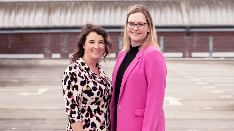 Two women smiling on a rooftop.