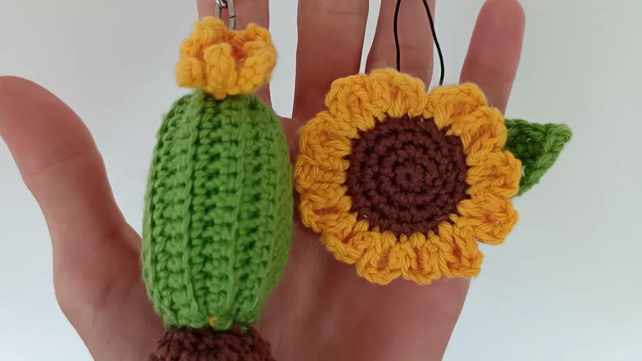 Hand hält gehäkelten Kaktus und Sonnenblume.