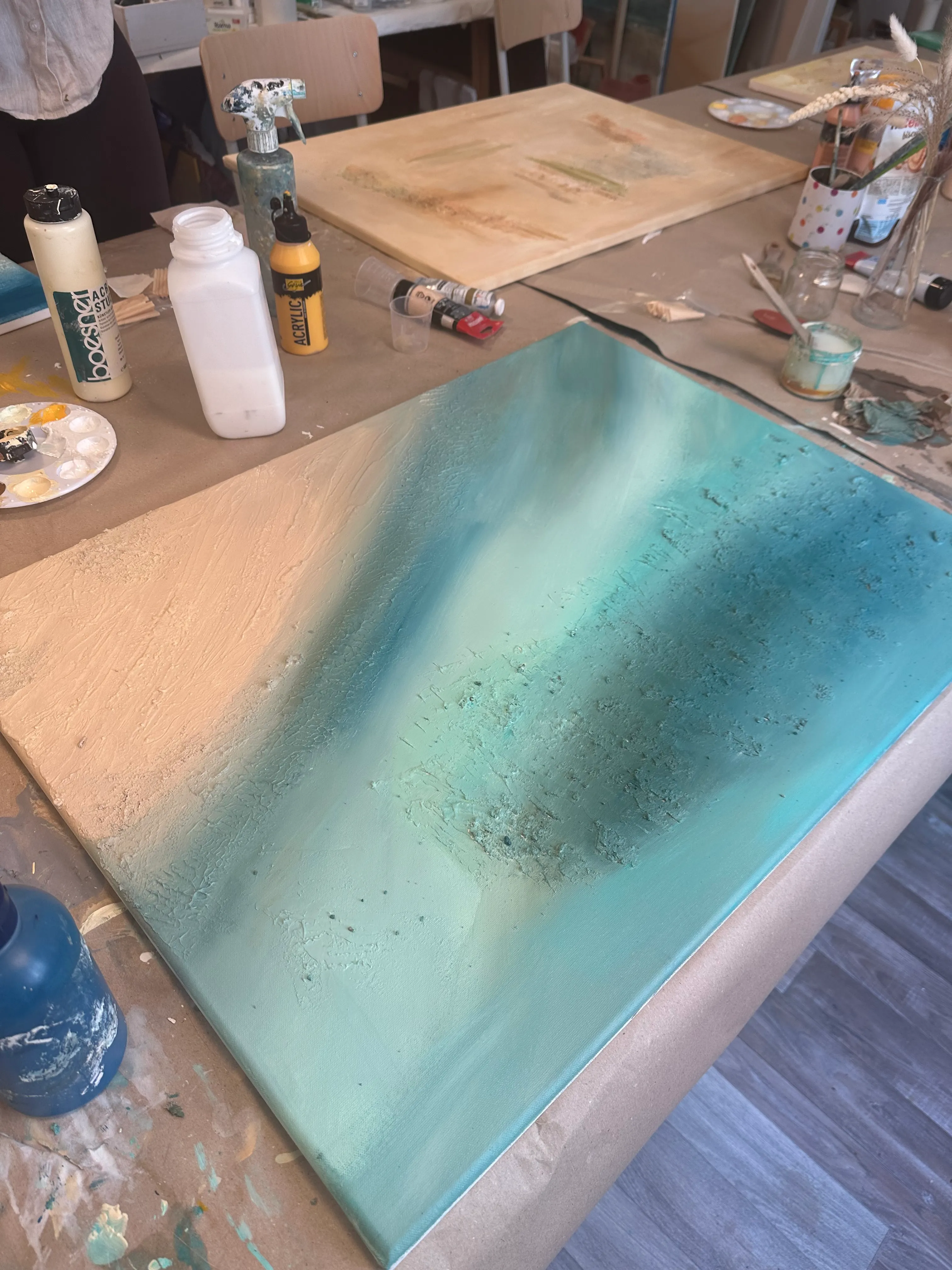 Abstraktes Gemälde auf Tisch mit Kunstmaterialien.