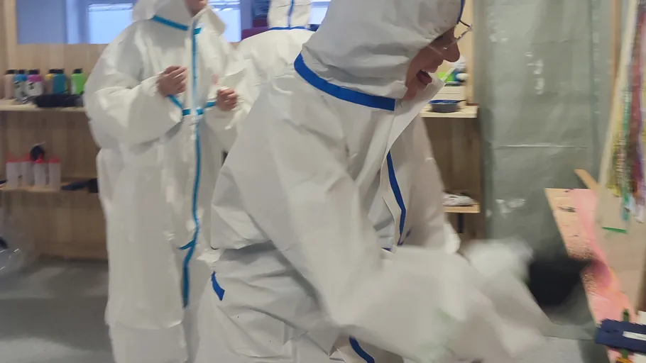 People in protective suits in a workshop.
