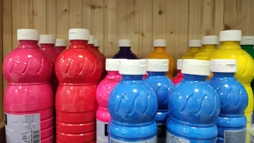 Colorful paint bottles on wooden shelves.