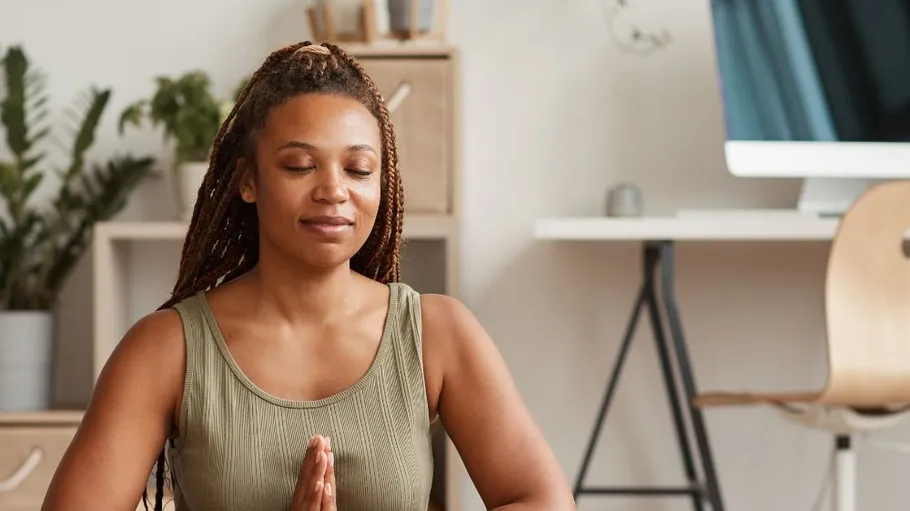 Woman meditating in a home office.