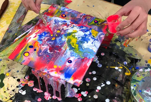 Hands creating colorful abstract paint art.