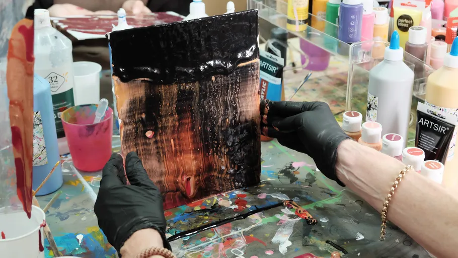 Person holding abstract painted sheet, creative workspace.