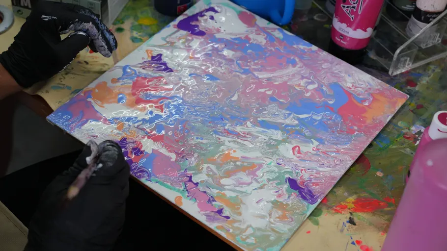 Person painting abstract art on a canvas.