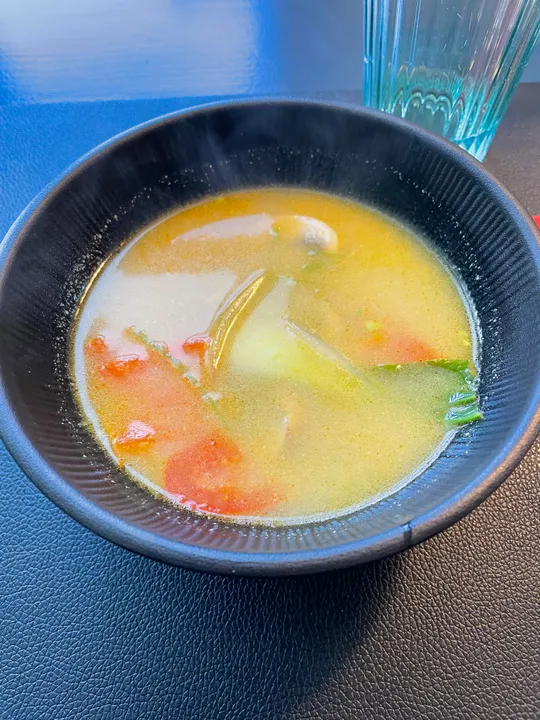 Bowl of soup with vegetables on table.