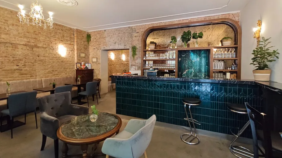 Schickes Café mit Backsteinwänden und grüner Bar.