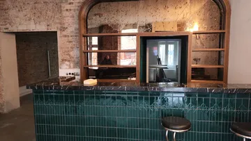 Leere Bar mit grünen Fliesen und Spiegel.