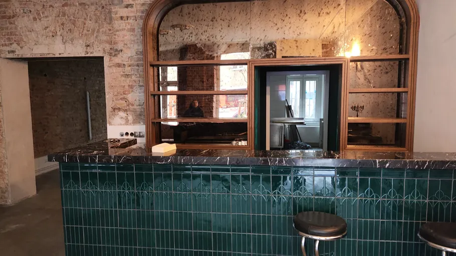 Empty bar with green tiles and mirror.