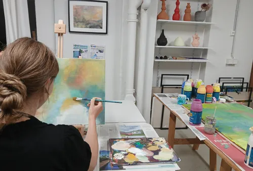 Frau malt auf Leinwand im Kunststudio.