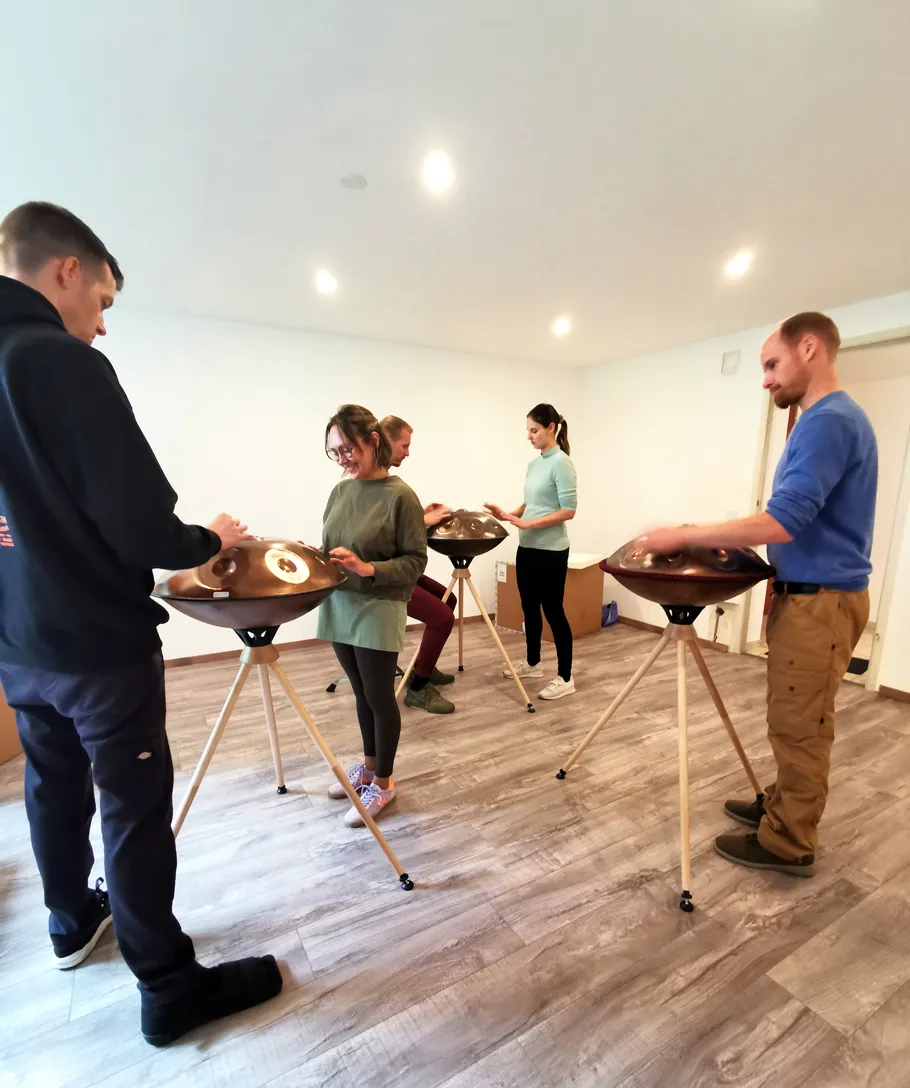People play handpans in a bright room.