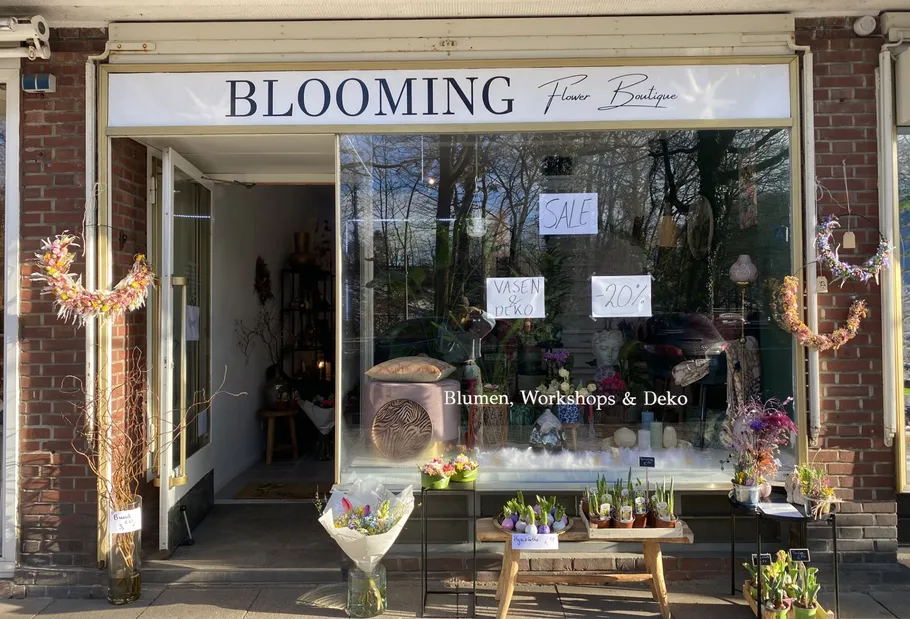 Blumenladen mit Verkaufsschildern im Fenster.