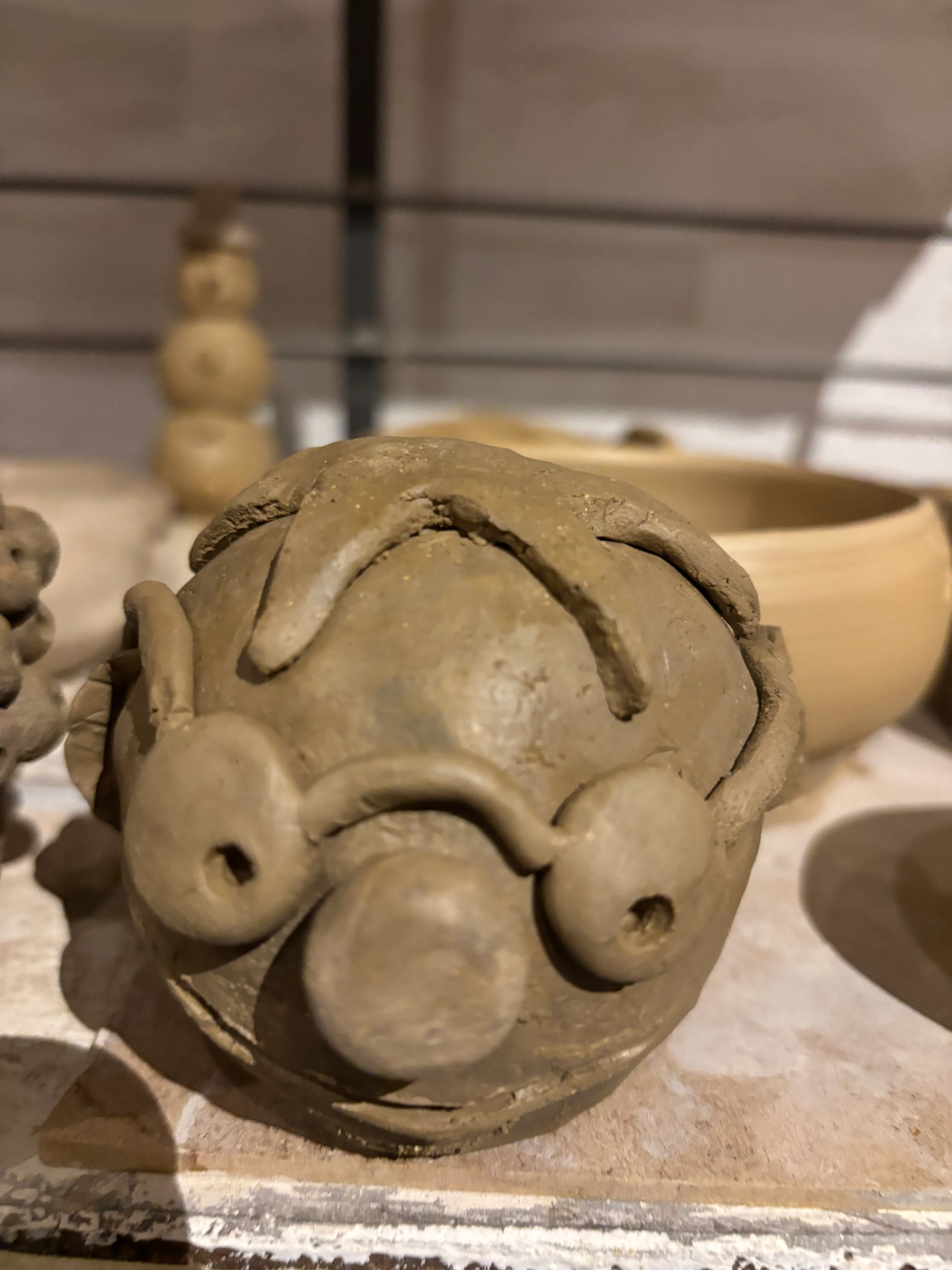 Tonfigur eines Gesichts auf einem Regal.