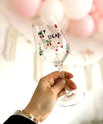 Hand holds decorated glass in festive setting.