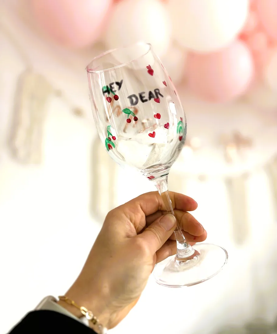 Hand hält verziertes Glas in festlicher Umgebung.
