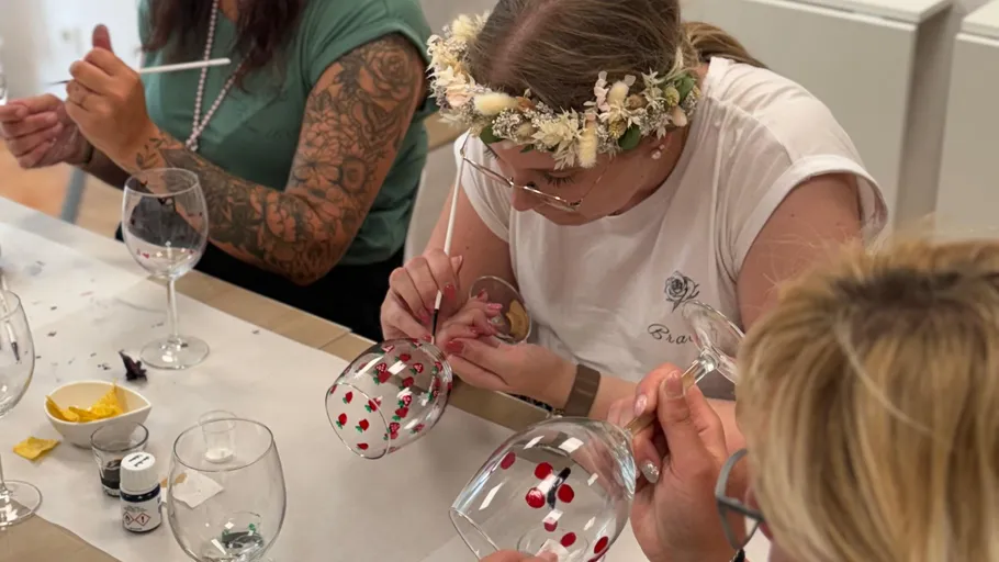 Frauen bemalen Weingläser in einem Workshop.