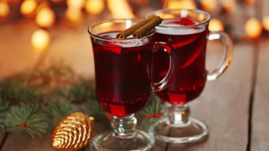 Two mulled wine glasses with cinnamon, festive background.