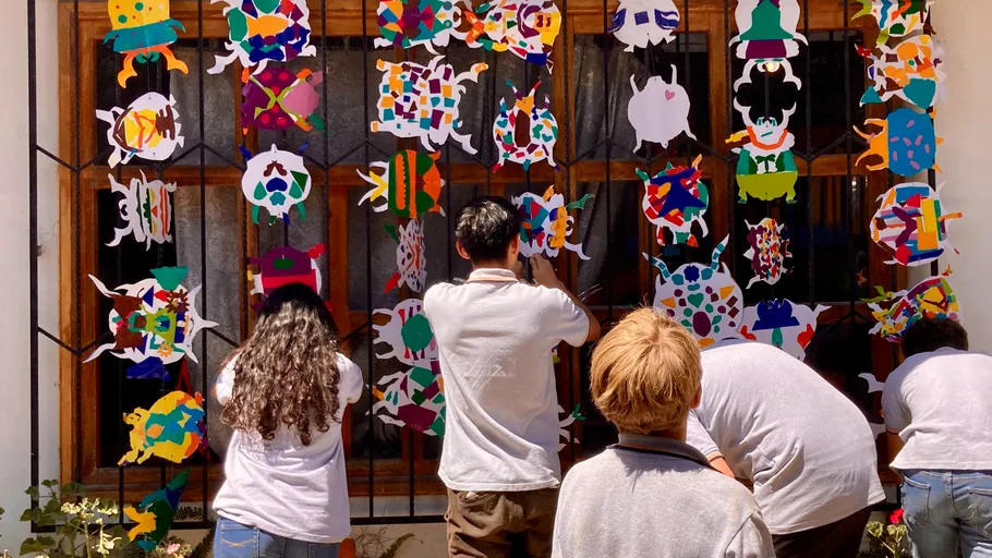 Children decorating colorful paper crafts on window.