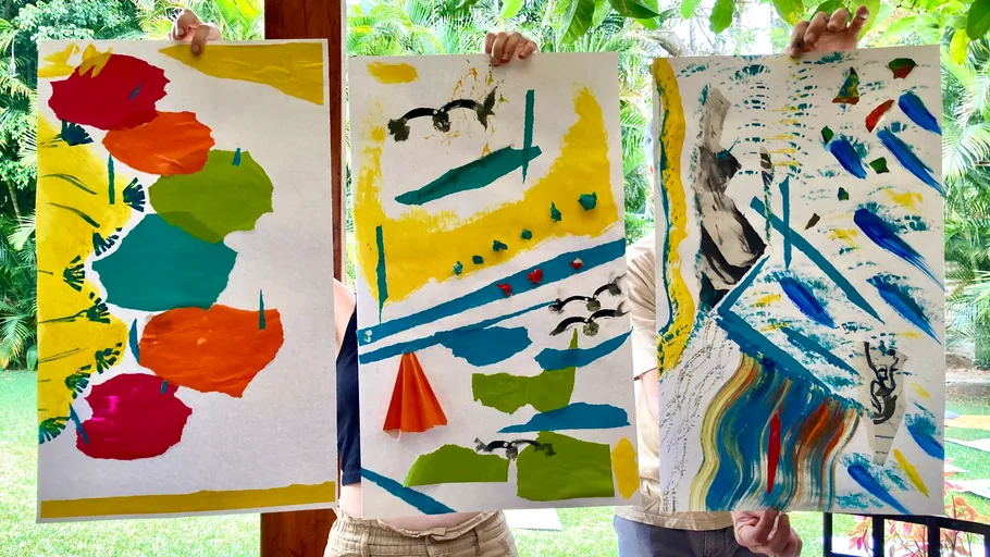 Three people holding abstract paintings outdoors.