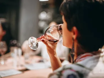 Glass with red wine is enjoyed by one person.