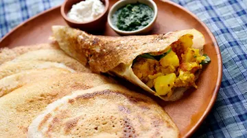 Dosa filled with potatoes on plate.