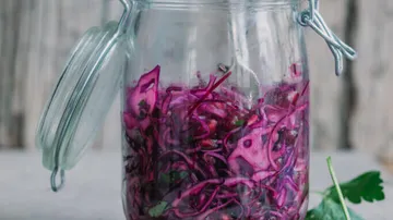 Jar with sliced red cabbage on table.
