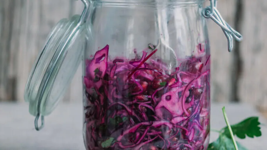 Jar with sliced red cabbage on table.
