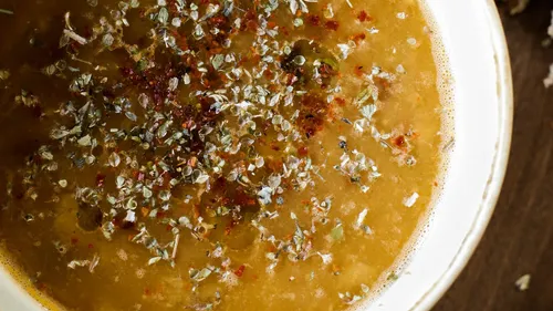 Soup with herbs in a white bowl.