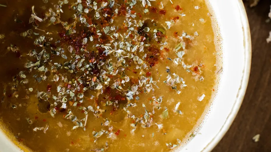 Suppe mit Kräutern in weißer Schale.