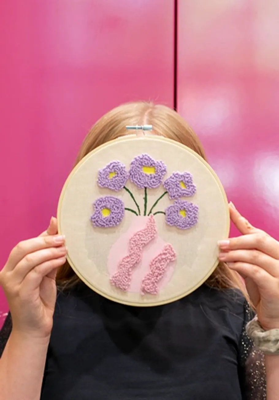 Person holding embroidery with floral design.