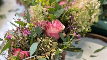 Gemischte Blumen mit pinken Rosen arrangiert.