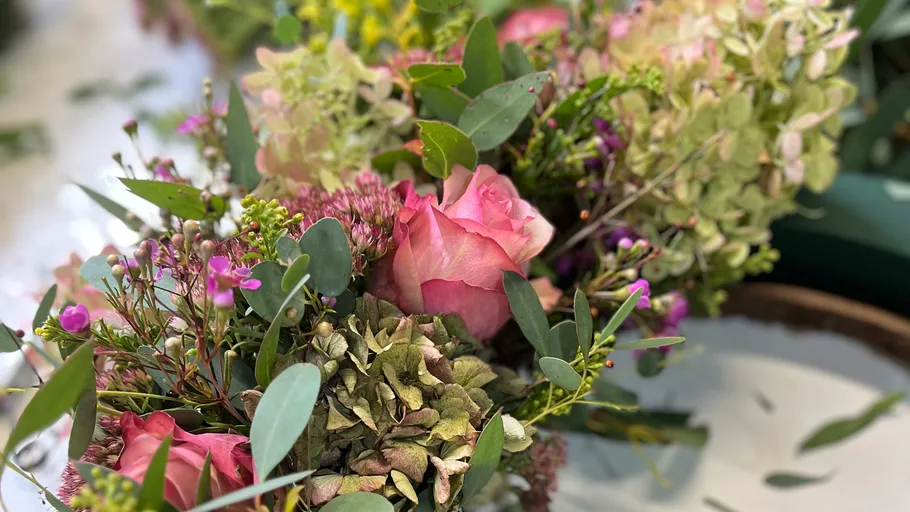 Gemischte Blumen mit pinken Rosen arrangiert.