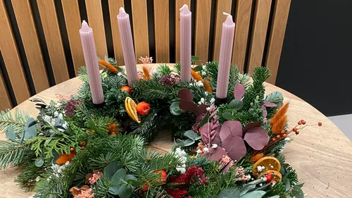 Advent wreath with pink candles on table.