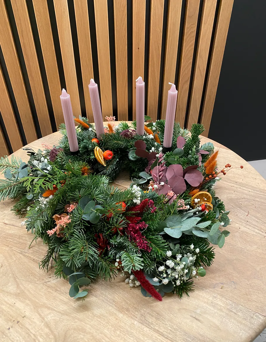 Adventskranz mit rosa Kerzen auf Tisch.
