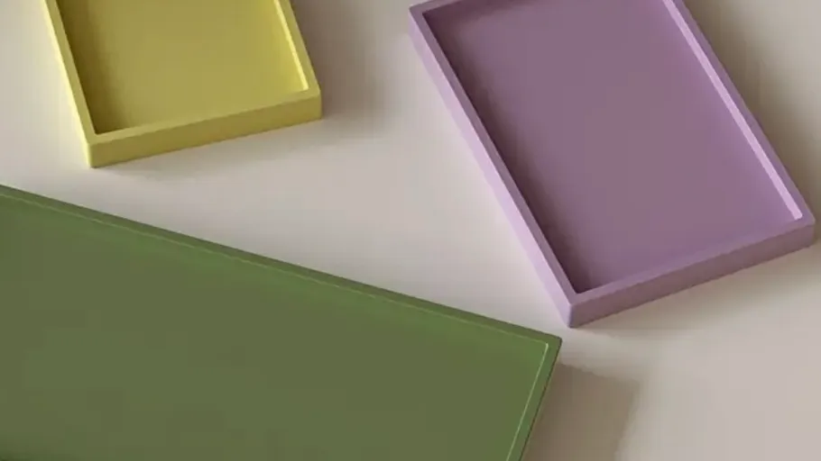 Drei bunte rechteckige Tabletts auf einem Tisch.