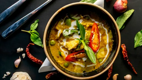 Thai curry with vegetables and herbs on plate.
