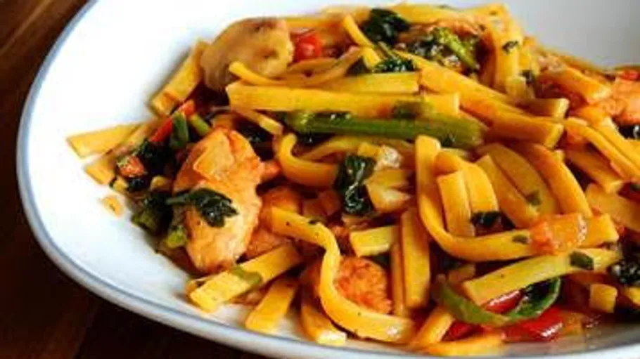 Noodles with chicken and vegetables on plate.