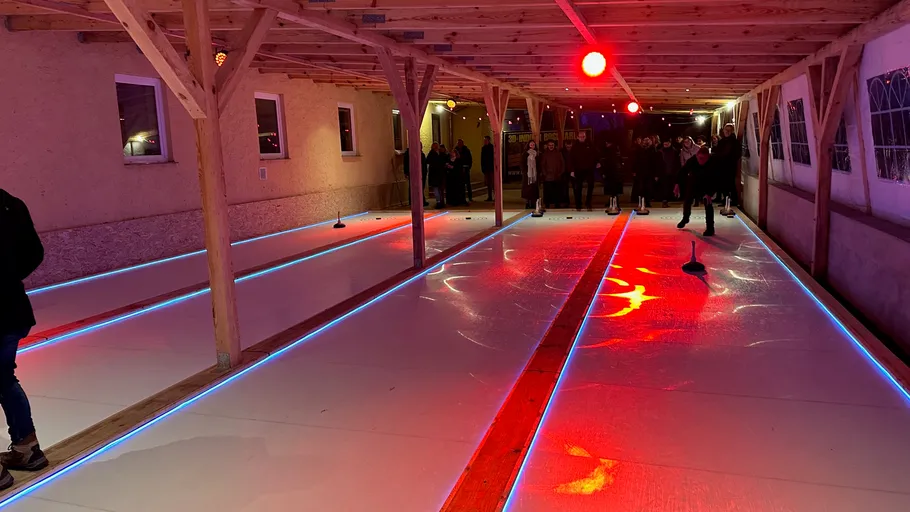 Überdachte Eisbahn mit Menschen beim Spiel.