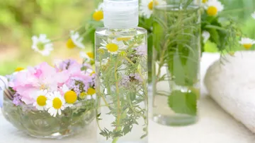 Flaschen mit Kräutern und Blumen im Freien.