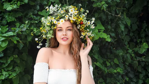 Frau mit Blumenkron, blättrigem Hintergrund.