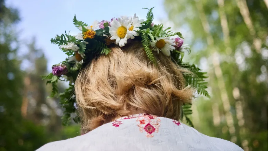 Person trägt Blumenschmuck draußen in der Natur.