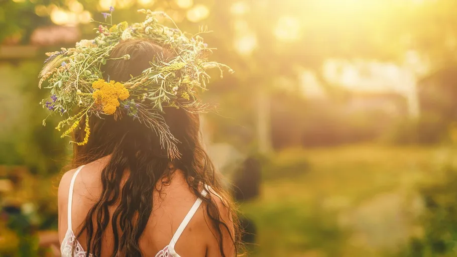 Woman with floral wreath in sunny garden.