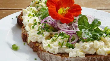 Bread topped with egg salad, onions, and flower.