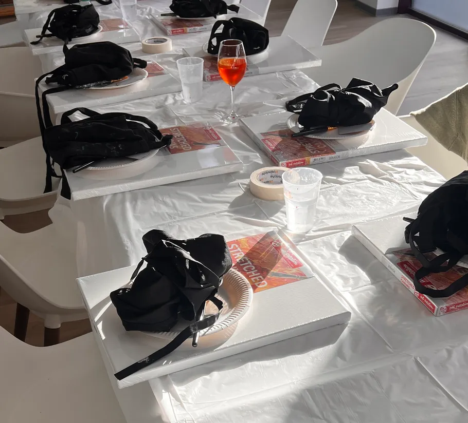 Kunstbedarf auf Tischen mit Getränken im Sonnenlicht.