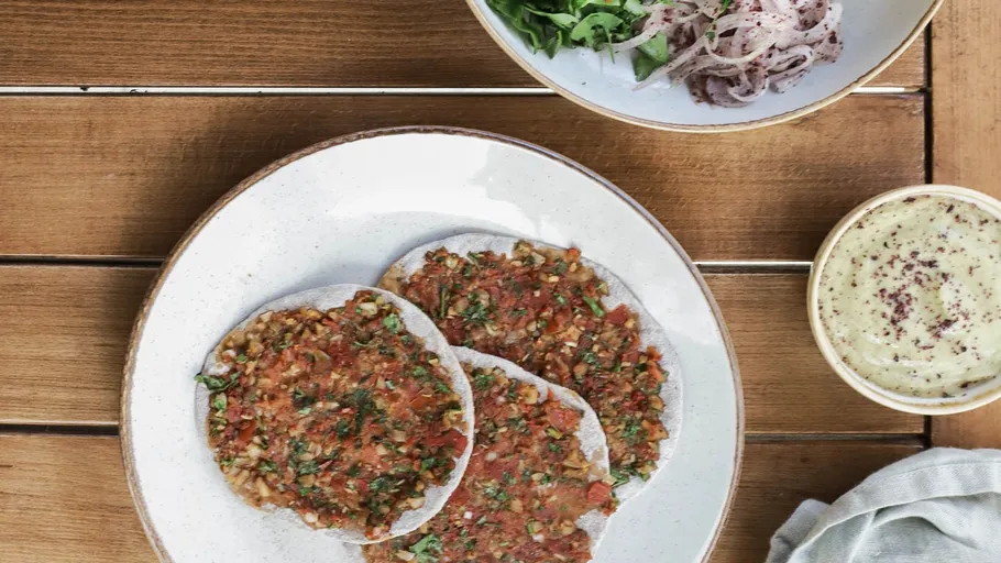 Türkische Pizzen auf Teller, Salat und Dip daneben.