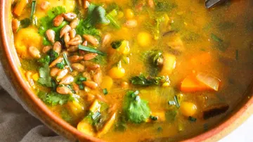Soup with vegetables and seeds in bowl.