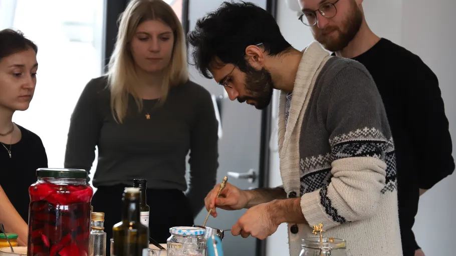 Mann mischt Zutaten im Glas, beobachtet von anderen.