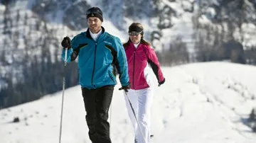 Zwei Personen beim Skilanglauf auf verschneitem Berg.